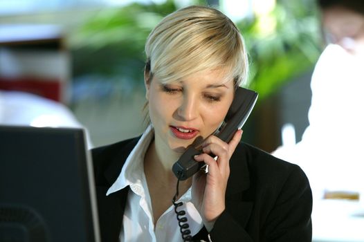 Blond office worker using land-line telephone