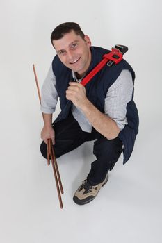 A plumber with copper pipes and a wrench.