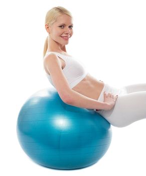 Beautiful teenage girl back stretch over exercise ball, looking at camera