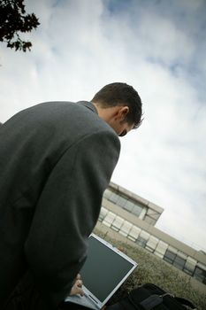 Businessman sat on grass with laptop