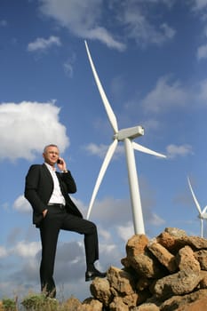 senior engineer phoning outdoors near windmills