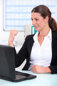 Young businesswoman delighted with what she can see on her computer screen