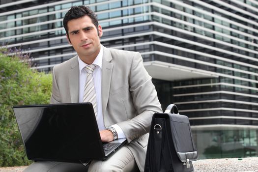 Businessman sat outside with laptop computer