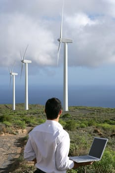 Man with computer watching wind turbines