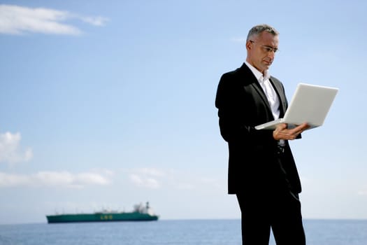 Businessman using his laptop at the coast