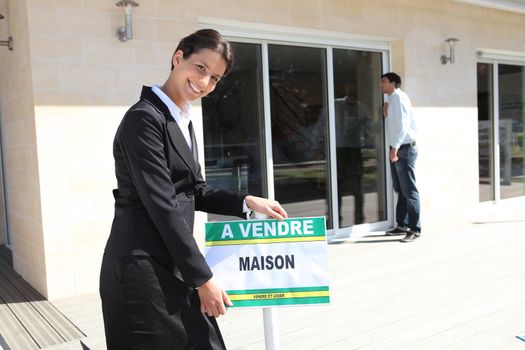 Estate agent with a French for sale sign