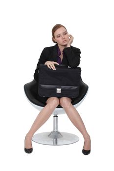 Austere businesswoman sitting in a chair with a briefcase on her lap