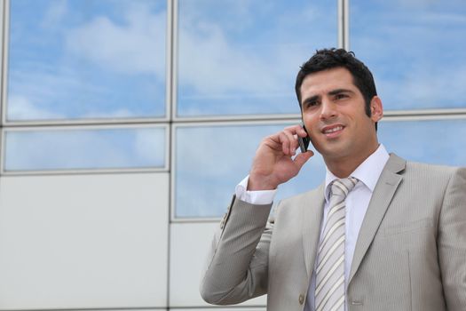 Man using a cellphone outside a mirrored building