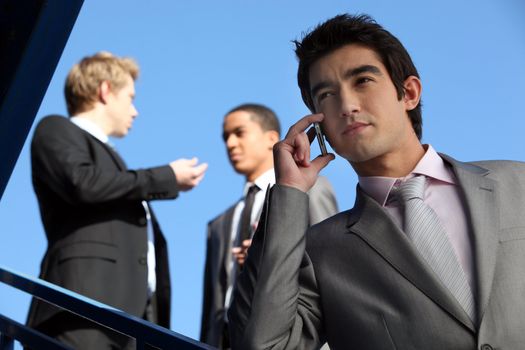 Three businessmen stood outside building