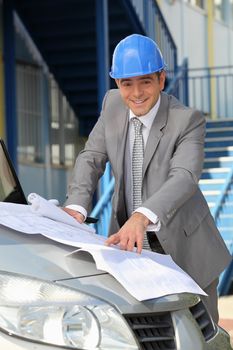 Architect looking at plans on a car bonnet