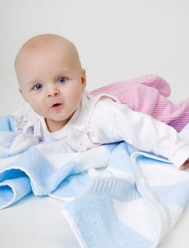 surprised beautiful baby lying on a blue towel
