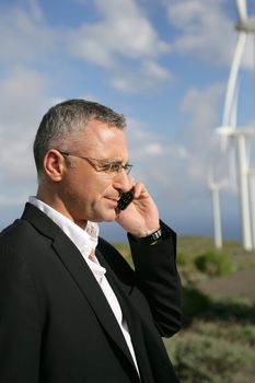Businessman talking on his mobile phone in a wind turbine park