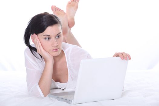 Girl laid on a bed with laptop