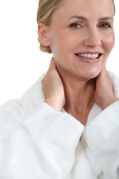 Woman in bath robe smiling with hands behind neck