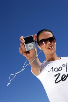 Brunette wearing sunglasses listening to music through mp3 player