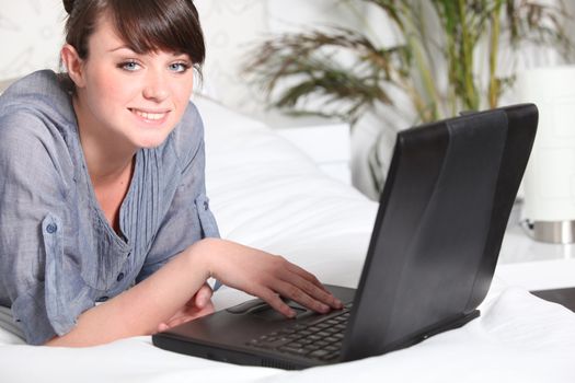 Cute woman using a laptop on her bed