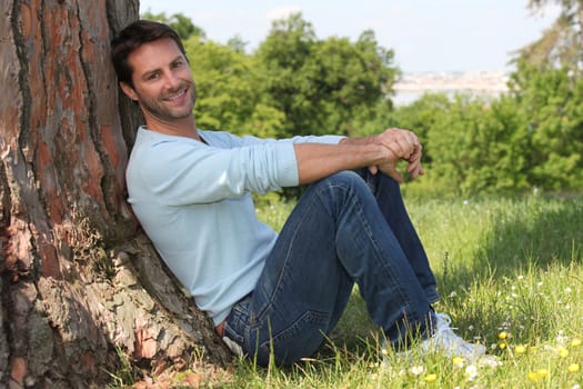 Man sitting against tree