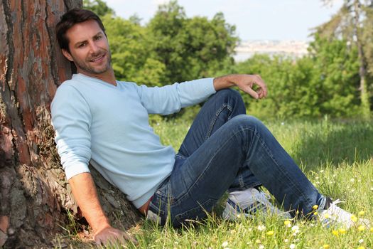 man sitting against tree
