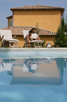 Mother and son poolside with laptop