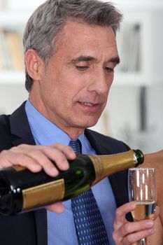 A mature man pouring champagne.