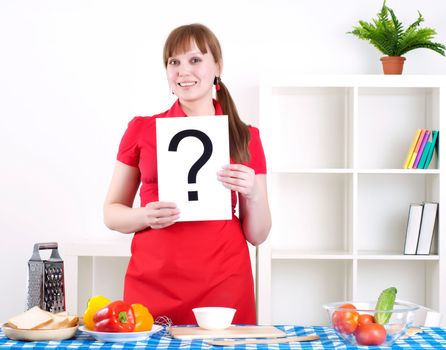 Young woman cooking fresh meal at home and holding question sign