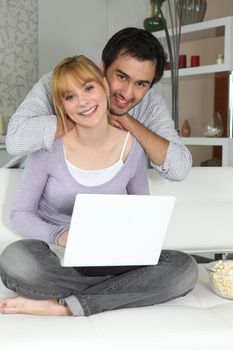 Young woman and young man smiling with laptop at home