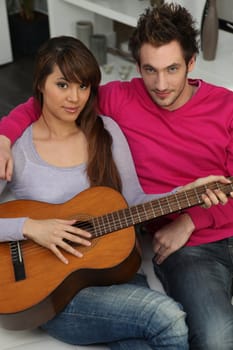 couple playing guitar at home