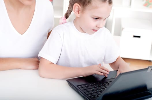 Mom and daughter are working together for a laptop at home