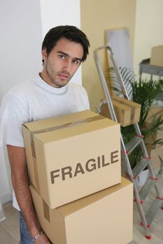 Young man carrying cardboard boxes on moving day