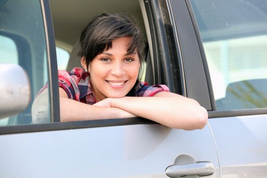 Young woman leaning out of the window of a car