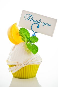 A refreshing lemon cupcake with a leaf of mint and a label for your text on white background as a studio shot