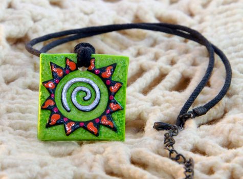 clay handmade green amulet (sun) on a knitted background