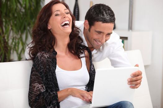 Couple laughing at their laptop