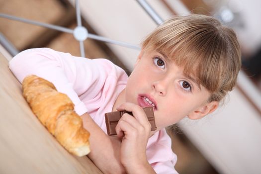 Young girl with a croissant and bar of chocolate