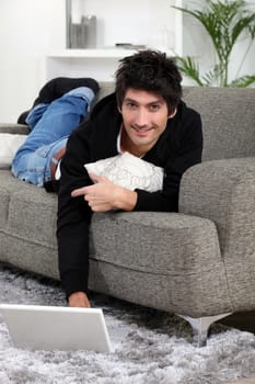 Man lying on a sofa with his laptop