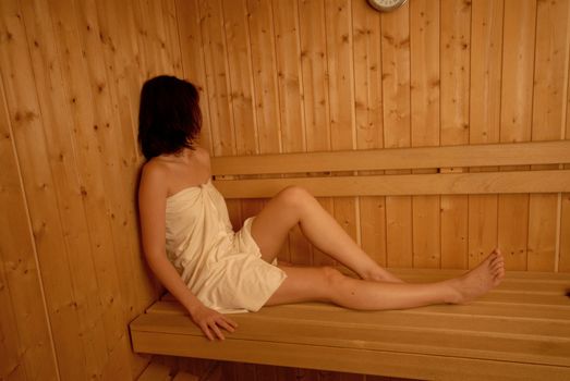 Girl relaxing in finnish type wooden sauna.