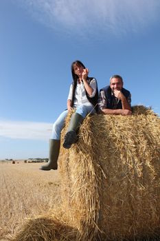 Couple sitting on bail of hay