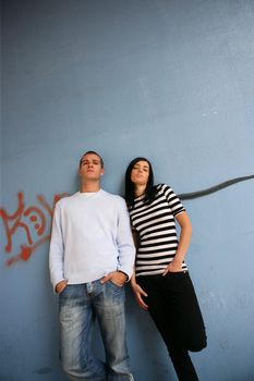 Young man and young woman leaning on a wall