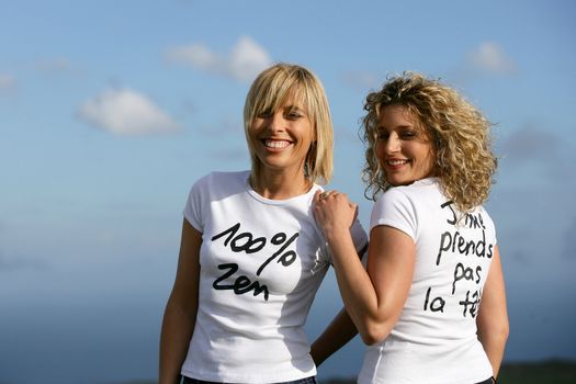 Women wearing slogan t-shirts against a blue sky