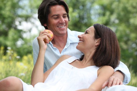 Happy couple relaxing in field