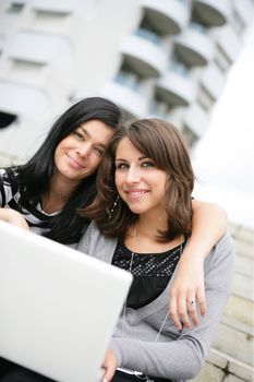 Two students using laptop on campus