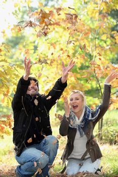 Couple playing with autumn leaves