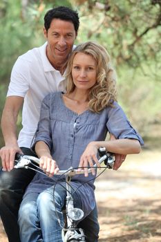 Couple riding bike in forest