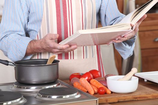 a man reading a recipe book in his kitchen
