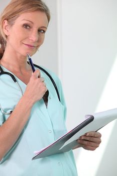 Smiling female nurse looking at notes