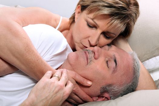 Woman kissing her sleeping husband