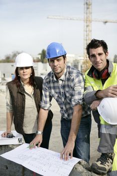 A team of tradespeople discussing a blueprint