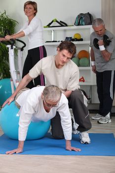 Older people working out with a personal trainer in a gym