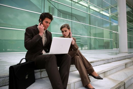 Young business couple sat on steps