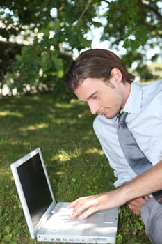Smart male executive using a laptop with a blank screen in the park